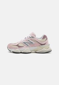 Pink and cream athletic shoe with suede and mesh materials, featuring a silver logo and textured accents, contoured sole, and laces.