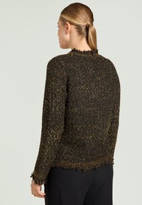 Black and gold textured knit sweater with a frayed hem, round neckline, and long sleeves, seen from the back against a light background.