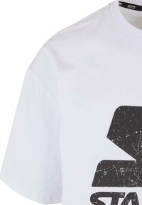 White cotton t-shirt with a loose fit, featuring a large black graphic print with distressed texture on the front. Short sleeves.