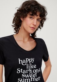 Schwarzes Baumwoll-T-Shirt mit Rundhalsausschnitt und weißem Textdesign: "glücklich wie Sterne an einem süßen Sommer." Kurze Ärmel, glatte Textur.