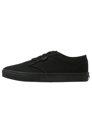Sort lavtopet lærreds-sneaker med sorte snørebånd og gummisål, sidevisning der viser øjer og syningsdetaljer.