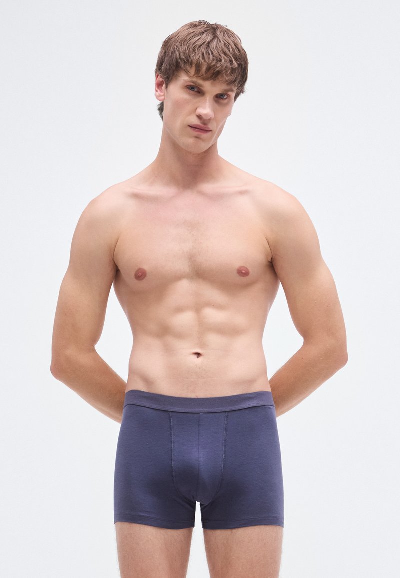 Calzoncillos tipo bóxer de algodón azul marino con una cinturilla suave y una costura frontal para mejor ajuste, que muestran una textura suave y un diseño ajustado.