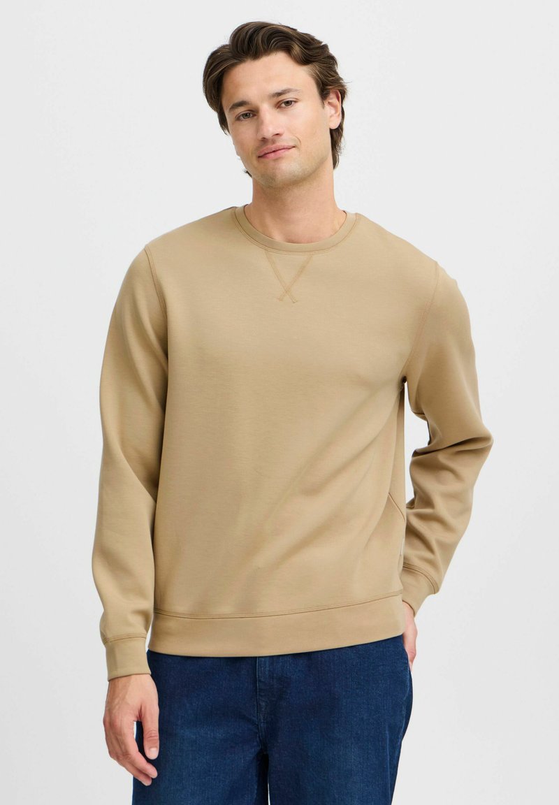 Beige sweatshirts med rund hals i et glat, bomuldsblandet materiale. Har ribbede manchetter og kant, med en subtil krydssyning ved halsen.