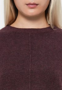 Bordowy sweter dzianinowy z prążkowaną fakturą, okrągłym dekoltem i centralnym szwem biegnącym pionowo wzdłuż przodu.