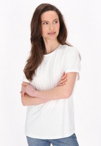 Hvid kortærmet T-shirt lavet af bomuld, med rund halsudskæring, opslåede ærmer og en afslappet pasform, parret med lyseblå jeans.