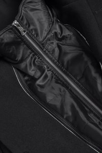 Intérieur d'une veste noire avec une doublure noire brillante, une fermeture éclair centrale et une texture douce, agrémenté d'un contour contrastant sur les bords.