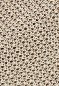 Beige kötött anyag, amely nyitott szövésű szerkezettel rendelkezik, és összefonódó szálakból álló textúrált mintát mutat, könnyű és légáteresztő minőséget biztosít.