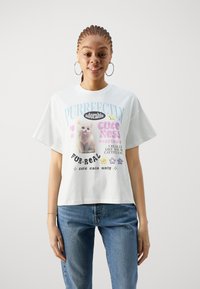 T-shirt en coton blanc avec des graphismes sur le thème des chats colorés, un texte ludique et une coupe décontractée avec des manches courtes légèrement oversize.