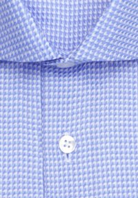 Chemise à col bleu à motif pied-de-poule blanc avec un bouton blanc près du centre.