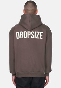 Brun hættebluse med stor hvid "DROPSIZE" tekst på ryggen, med snoretræk i hætten samt ribbet kant og manchetter.