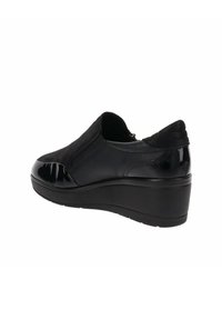 Scarpa nera slip-on con tomaia texturizzata, punta in vernice lucida e tacco basso per il comfort. Presenta pannelli laterali elastici per un facile indossamento.