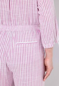 Raidohaalari vaaleanpunaisena ja valkoisena raidoitettuna. Varustettu joustavalla vyötäröllä ja pienellä takataskulla. Kangas näyttää kevyeltä ja teksturoidulta.