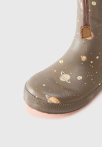 Botas de goma marrones con estampados de planetas y estrellas coloridos, suela texturizada, punta redonda y un ribete naranja en contraste en la base.
