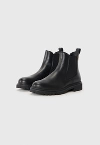 Bottes Chelsea en cuir noir avec des panneaux élastiques sur les côtés, bouts ronds et semelles en caoutchouc robustes. Elles sont dotées de tirettes pour un enfilage facile.