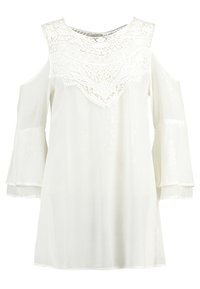 Blouse blanche à épaules dénudées, avec des détails en dentelle élaborés au niveau du col, et des manches longues et évasées, fabriquée dans un tissu léger.