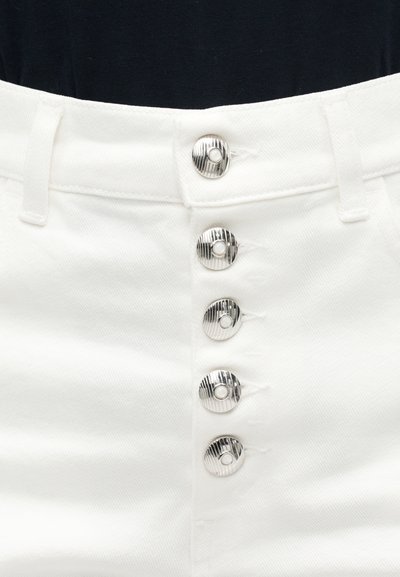 Λευκό τζιν παντελόνι με πέντε κάθετα ασημένια κουμπιά και θηλιές για ζώνη στη μέση, ορατό πάνω σε σκουρόχρωμο φόντο top.