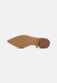 Nude High-Heel-Schuh mit spitzem Zehenbereich, glattem Lederobermaterial und einer Gummisohle mit strukturiertem Muster für besseren Halt.