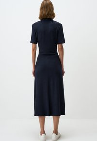 Robe tricotée bleu marine à manches courtes, corsage ajusté et jupe midi fluide. Elle présente une texture lisse et un design simple et classique.