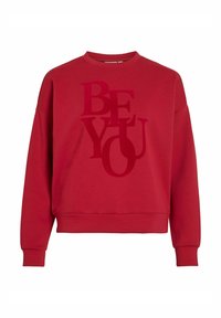Sweatshirt en coton rouge avec un col rond et des épaules baissées. Présente un grand graphique "SOIS TOI" en tons variés. Texture douce.