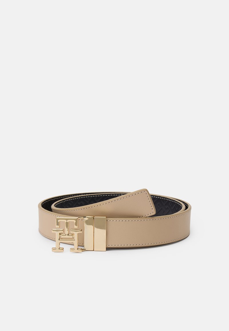 Ceinture en cuir beige avec une boucle dorée présentant un logo entrelacé. Le côté intérieur a un motif texturé noir.