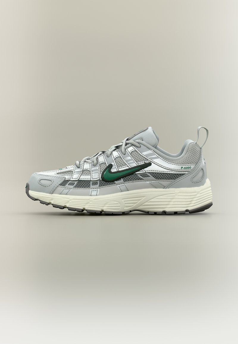 Chaussure de sport gris clair avec logo Nike swoosh vert, détails en mesh, semelle blanche épaisse et inscription "P-6000" sur le côté du talon.