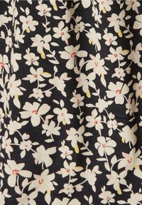 Tissu en coton avec un fond bleu marine orné de motifs floraux blancs et roses, avec des accents jaunes et une surface texturée.