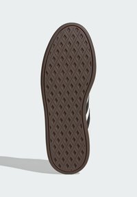 Brown rubber shoe sole featuring a diamond pattern with a smooth edge, detailing ridges and a slightly curved shape for traction.