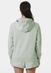 Sudadera verde menta con una textura suave, capucha ajustable y mangas raglán. Combinada con pantalones cortos a juego, presenta un corte relajado.