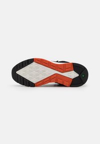 Semelle de basket avec un motif noir, blanc et orange, texture en relief et logo Timberland embossé près du talon.