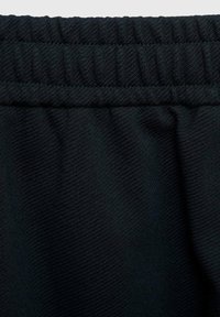 Zwarte sportshorts van een textuur oppervlak, met een opgetrokken elastische tailleband en gladde naden, die een flexibele pasvorm bieden.