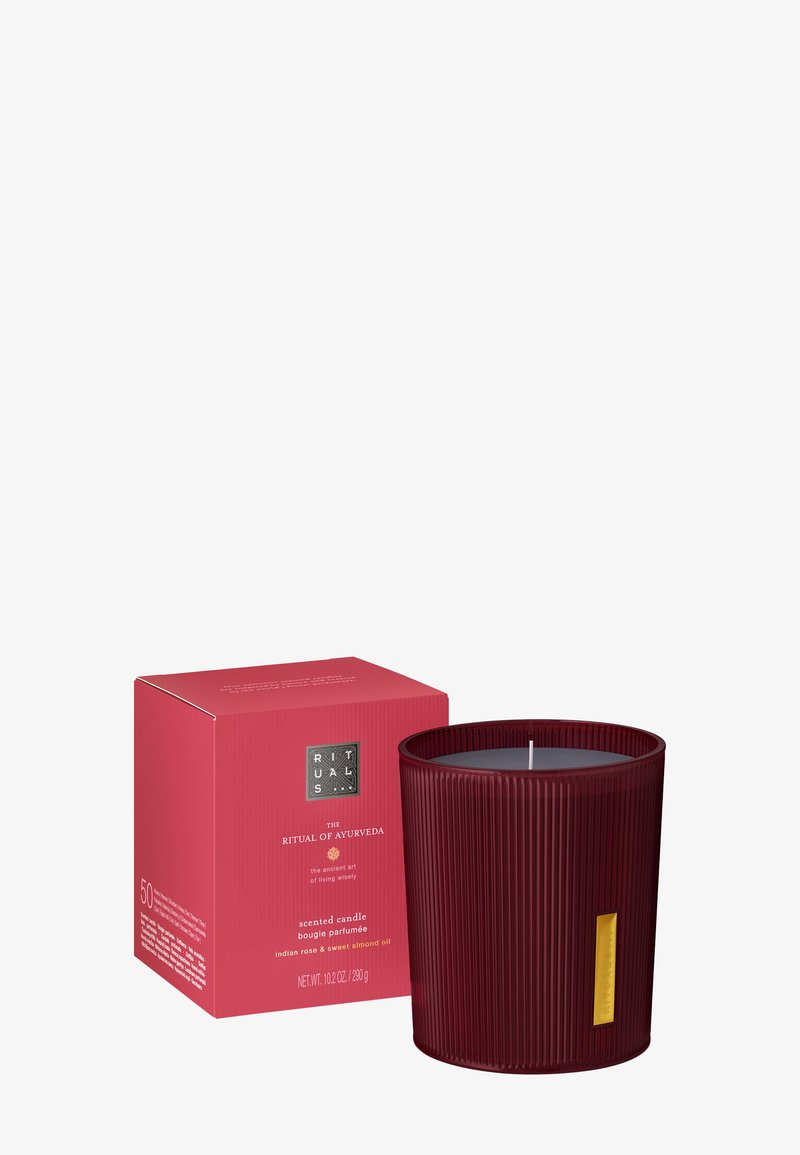 Rødt ribt glasslys med gullabel ved siden av matchende rød boks merket "The Ritual of Ayurveda," duftet med indisk rose og søt mandelolje.
