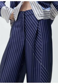 Pantaloni a righe blu navy con un design sartoriale, dotati di pieghe nette, righe bianche in contrasto e una texture liscia e satinata.