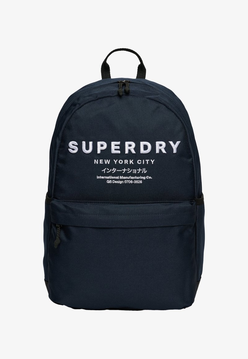 Marineblauwe stoffen rugzak met een ronde vorm, voorzien van het witte geprinte logo "SUPERDRY" en een voorste ritszak voor opberging.