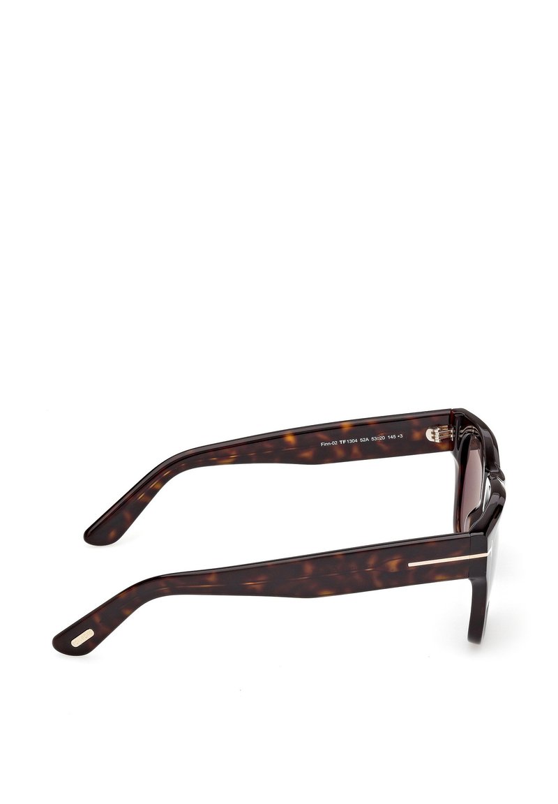 Lunettes de soleil écaille de tortue avec de larges montures rectangulaires, des verres foncés et des branches élégantes ornées d'un accent métallique près de la charnière.