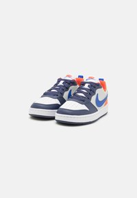 Nike sneakers with a navy and white leather upper, accented by orange and blue details. Perforated toe cap and flat laces. Flat rubber sole.