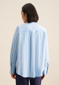Camicia a righe blu chiaro realizzata in tessuto morbido, con maniche lunghe, yoke e vestibilità comoda con orlo curvo.