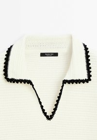 Col en tricot blanc avec bordure noire festonnée et étiquette noire indiquant "Massimo Dutti Fabriqué en Chine"