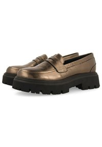Mocasines metálicos en bronce con una suela de goma negra gruesa, que presentan una punta redondeada y costuras decorativas en la parte superior.