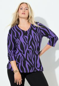 Czarny i fioletowy top z długim rękawem z wzorem zebry, dekoltem w szpic i luźnym krojem. Tkanina wydaje się miękka o gładkiej fakturze.