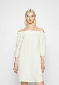 Vestido creme com ombros à mostra, decote com babados, mangas de três quartos e tecido texturizado, apresentando um corte solto e comprimento até o joelho.