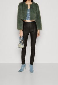 Grøn faux fur cropped jakke, blå paillet crop top, sorte læder leggings og lyseblå hæl-støvler. Lille blå håndtaske inkluderet.