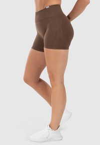 Bruine aansluitende shorts met een hoge tailleband, gemaakt van rekbaar materiaal. Soepele textuur, ontworpen voor comfort en bewegingsvrijheid.
