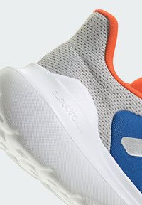 Baskets de sport en maille grises avec des accents orange, une semelle en caoutchouc blanc et des détails bleus. Présente le logo Cloudfoam sur le côté.