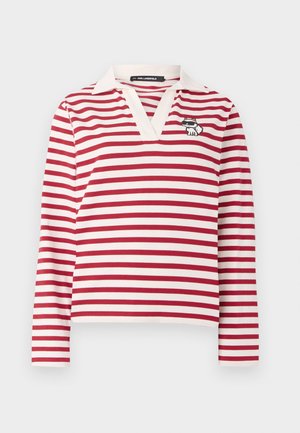 Camisa de manga larga a rayas rojas y blancas con escote en V y un collar blanco. Presenta un pequeño diseño bordado de un gato en el lado izquierdo.