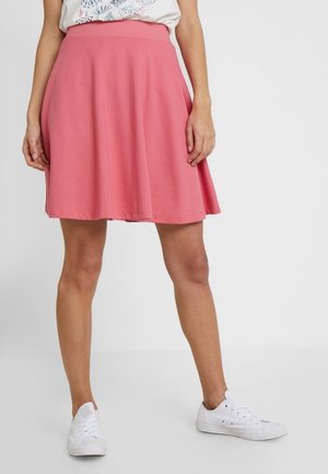 Roze A-lijnrok van gestructureerde stof, met een rekbare tailleband en een uitlopende silhoet, gecombineerd met witte sneakers.