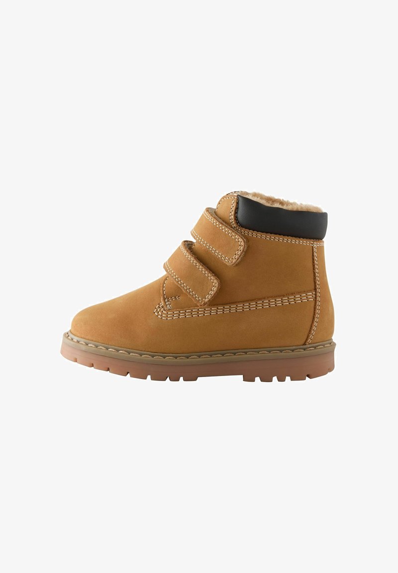 Botte d'hiver en daim beige avec deux sangles velcro, col noir, détails cousus et semelle épaisse en caoutchouc avec crampons pour une bonne adhérence.