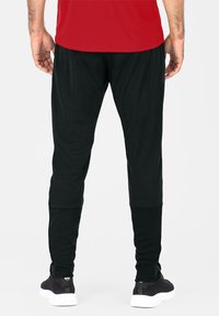 Schwarze Sporthose mit tailliertem Design, aus flexiblem Material, mit strukturierter Oberfläche und elastischen Knöchelbündchen.