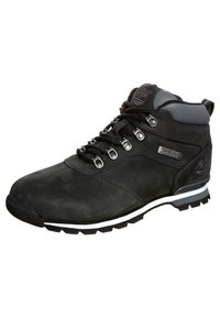 Botte d'extérieur noire en daim avec des accents gris, dotée d'œillets en métal, d'un col rembourré et d'une semelle en caoutchouc avec une bande blanche.