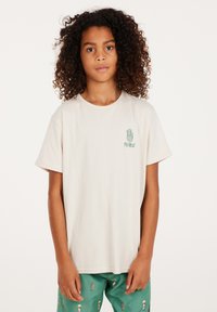 Lichtbeige katoenen T-shirt met korte mouwen, voorzien van een groene geprinte handontwerp en de tekst "PROTEST" op de linkerborst.