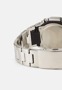 Stainless steel watch with a matte finish, linked bracelet design, and a black plastic section on the case. Features a secure clasp.